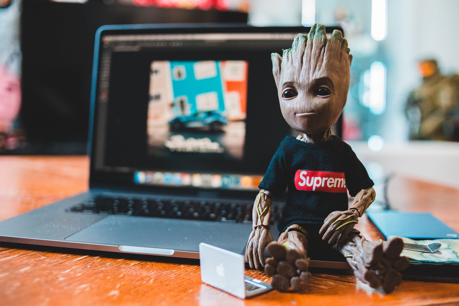 Groot action figure next to laptop.